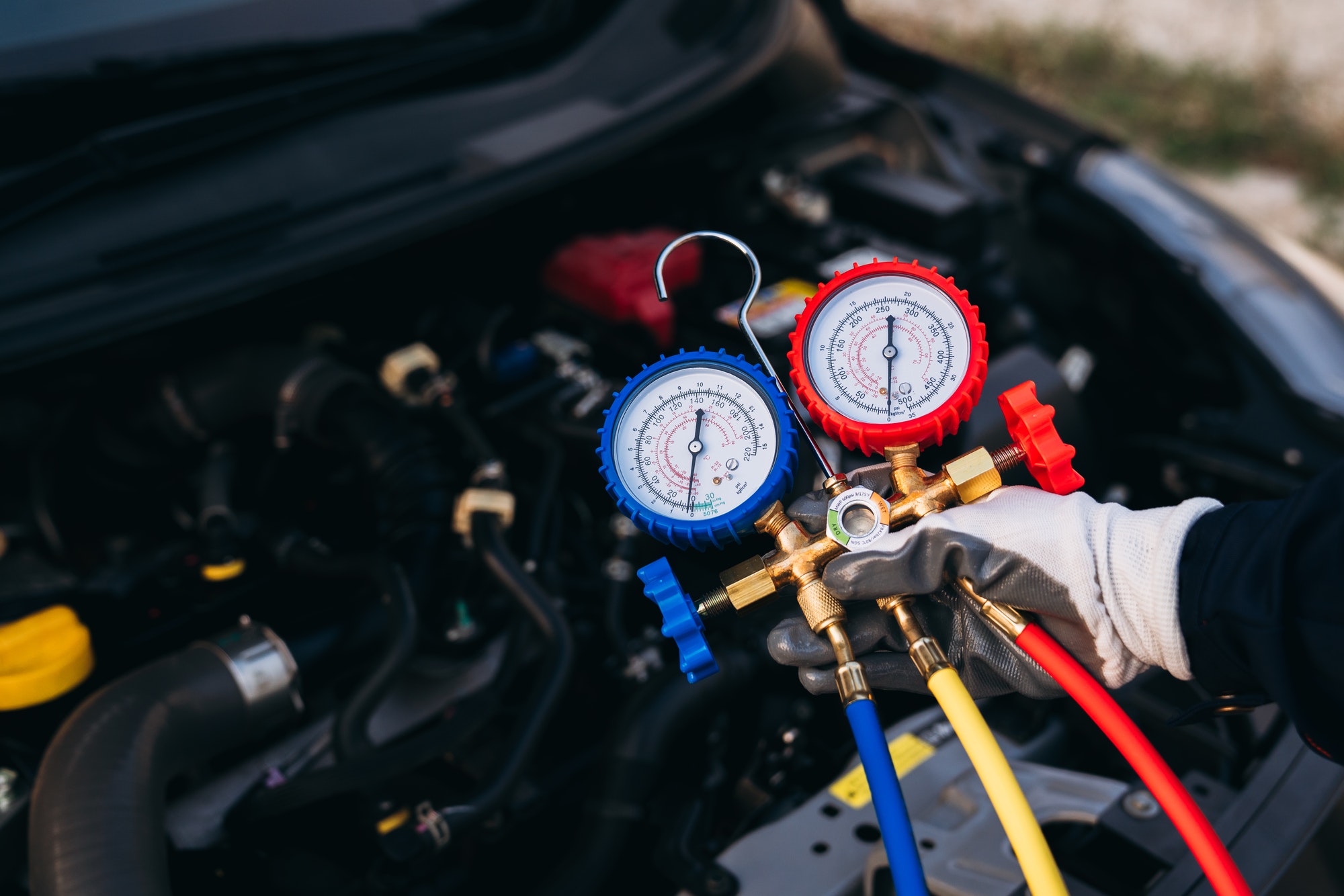 Close up hand of Mechanics inspect and check the refrigerant and fill the car air conditioner.